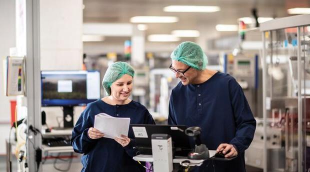 Two laboratory technicians looking at a laptop